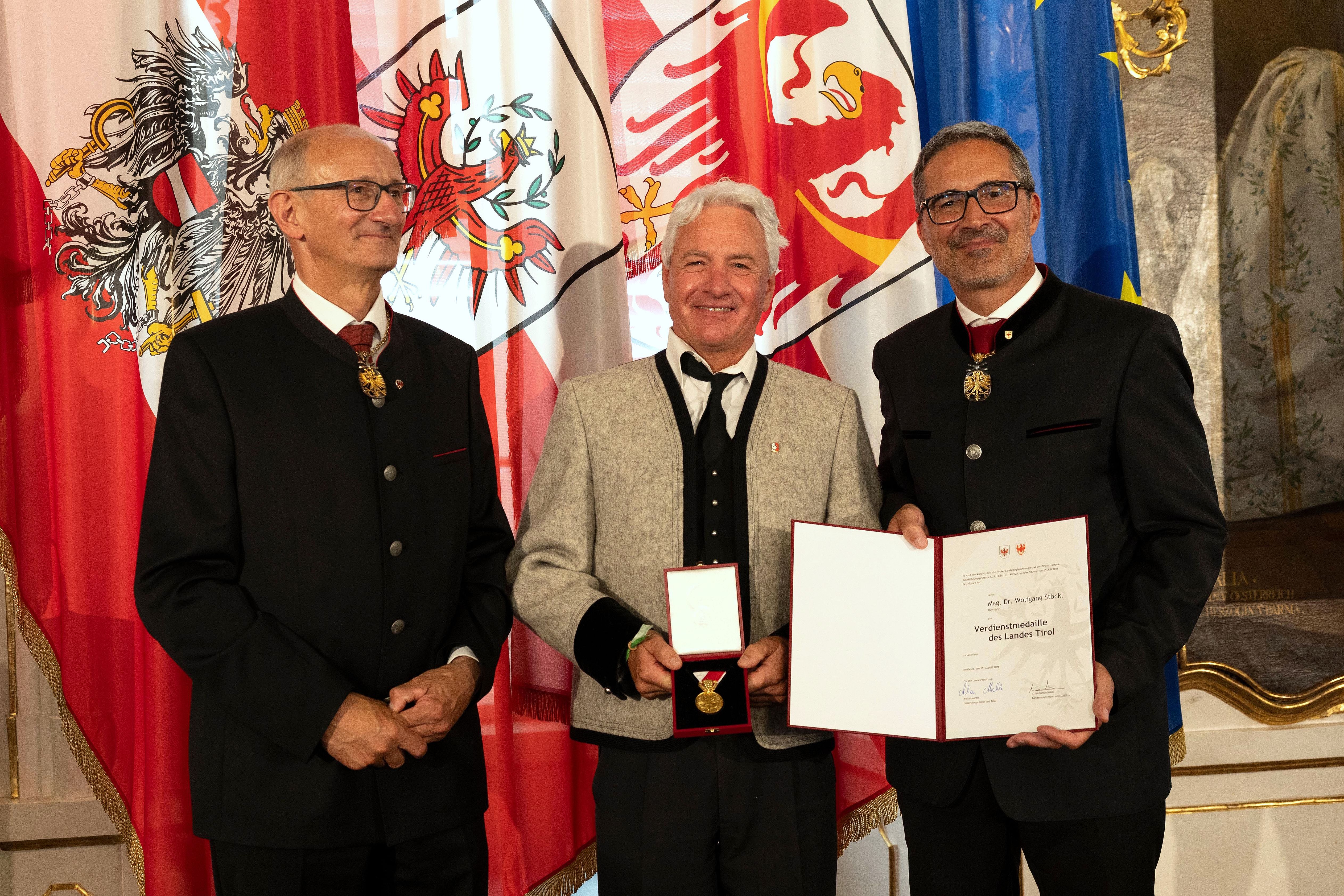 Landeshauptmann Anton Mattle und Südtirols Landeshauptmann Arno Kompatscher überreichen Mag. Dr. Wolfgang Stöckl die Verdienstmedaille des Landes Tirol.